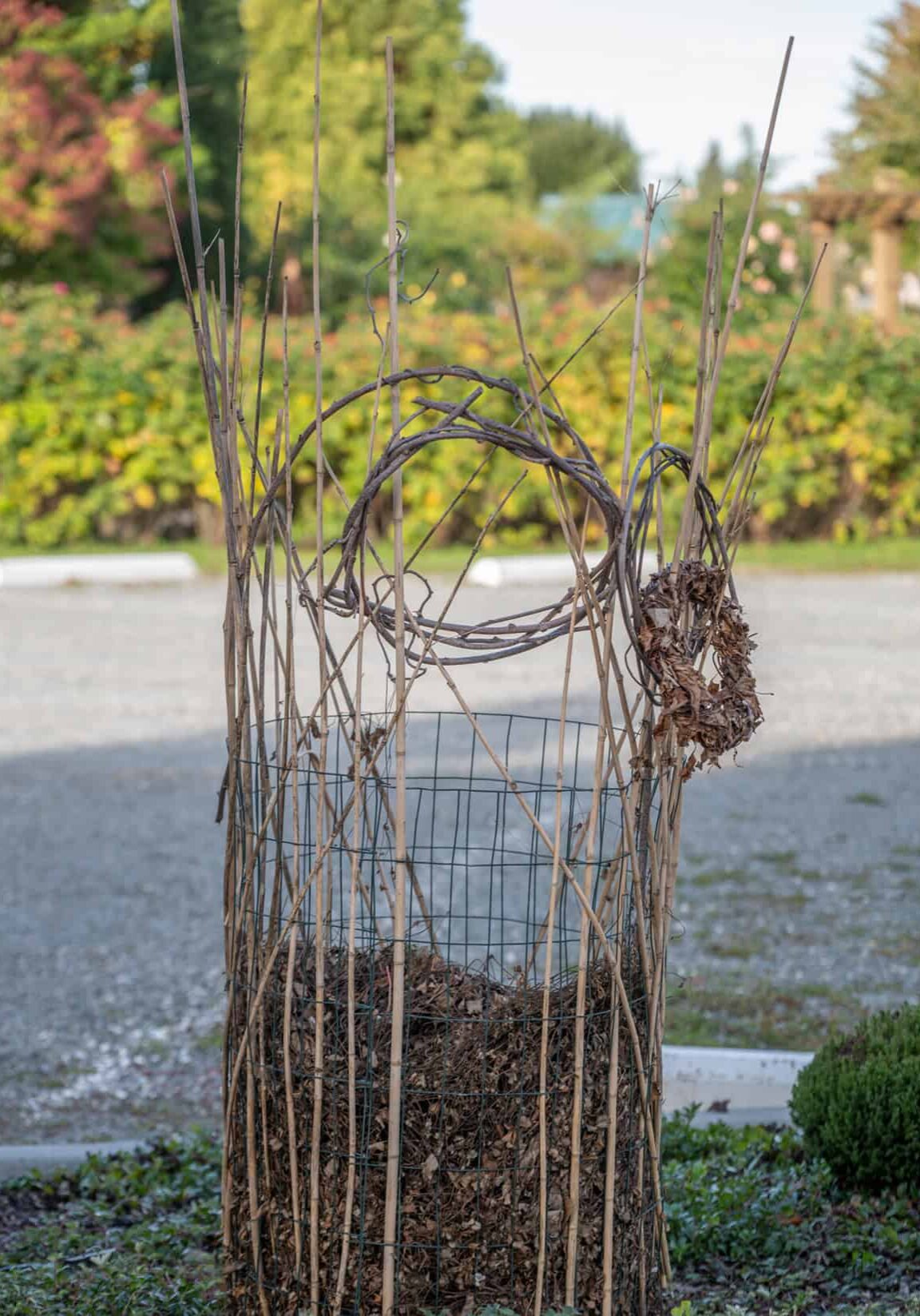 compost tower with twigs and vines woven through wire cage holding compost leaves