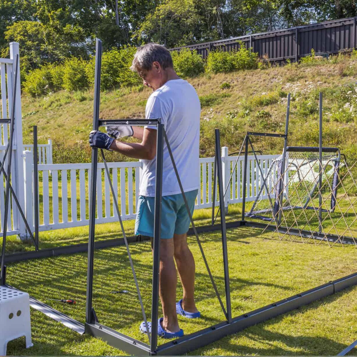 person using tools to assemble a greenhouse frame