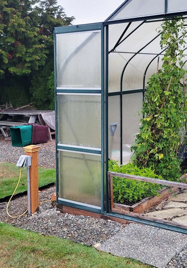 greenhouse with door open and electrical box on post outside