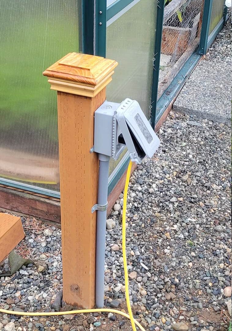close up of electrical box on post with cords running to greenhouse