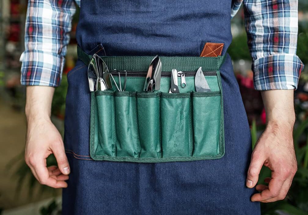 person wearing apron with gardening tools in pocket