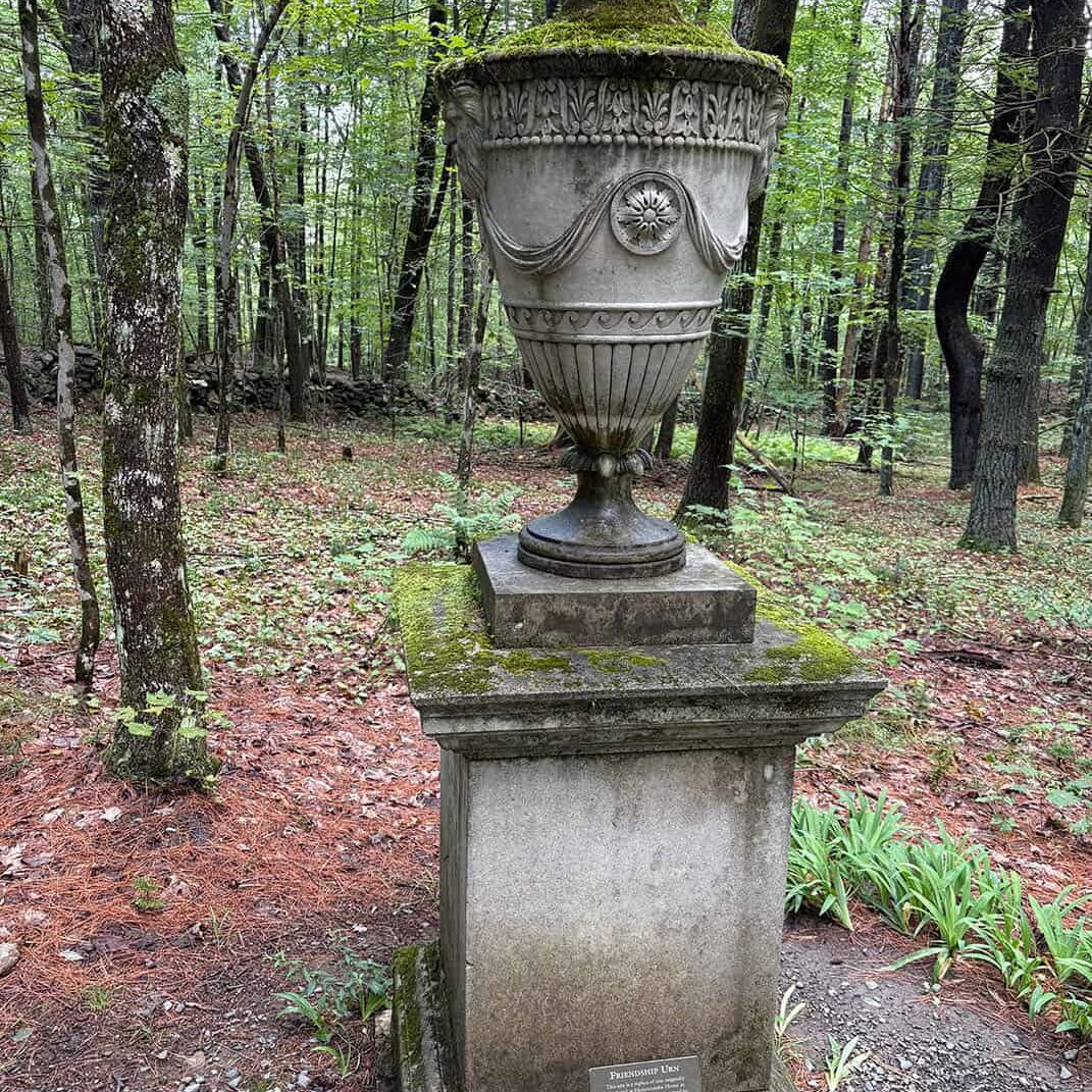large cement urn on path in woods